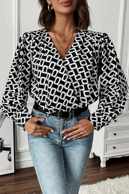 A folded black Nadia patterned long sleeve blouse, illustrating its compact storage and easy-care material.