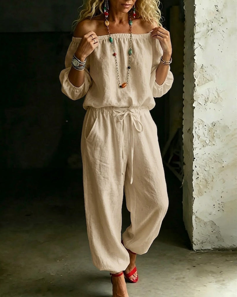Model sitting comfortably in the Rhiannon off-shoulder cotton jumpsuit, demonstrating its ease of wear.