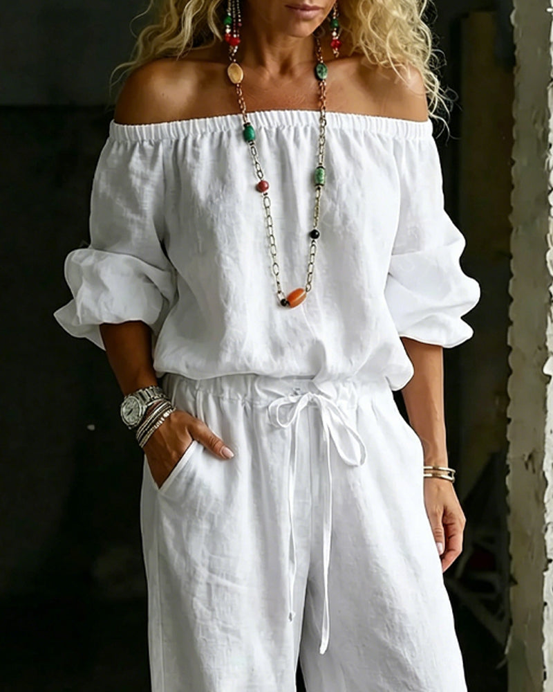 Side profile of a model wearing the comfortable Rhiannon off-shoulder cotton jumpsuit, highlighting the wide leg and drape of the fabric.