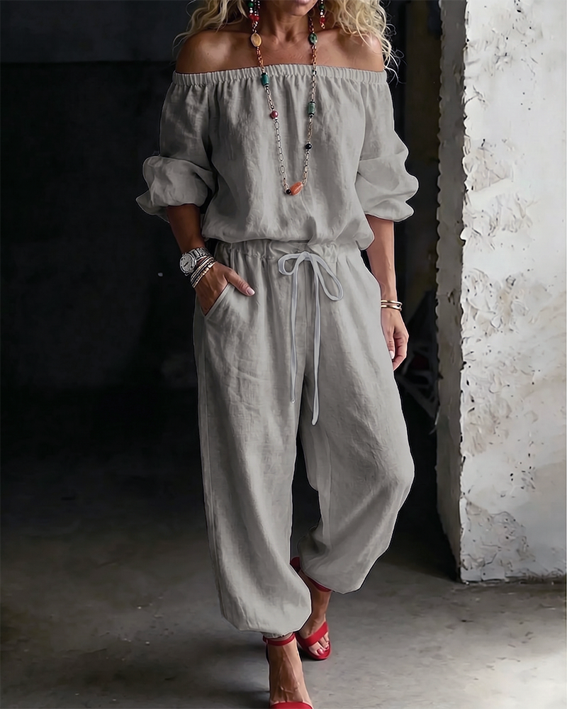 Model enjoying a leisurely moment outdoors while wearing the Rhiannon off-shoulder cotton jumpsuit.