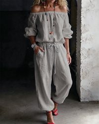 Model enjoying a leisurely moment outdoors while wearing the Rhiannon off-shoulder cotton jumpsuit.