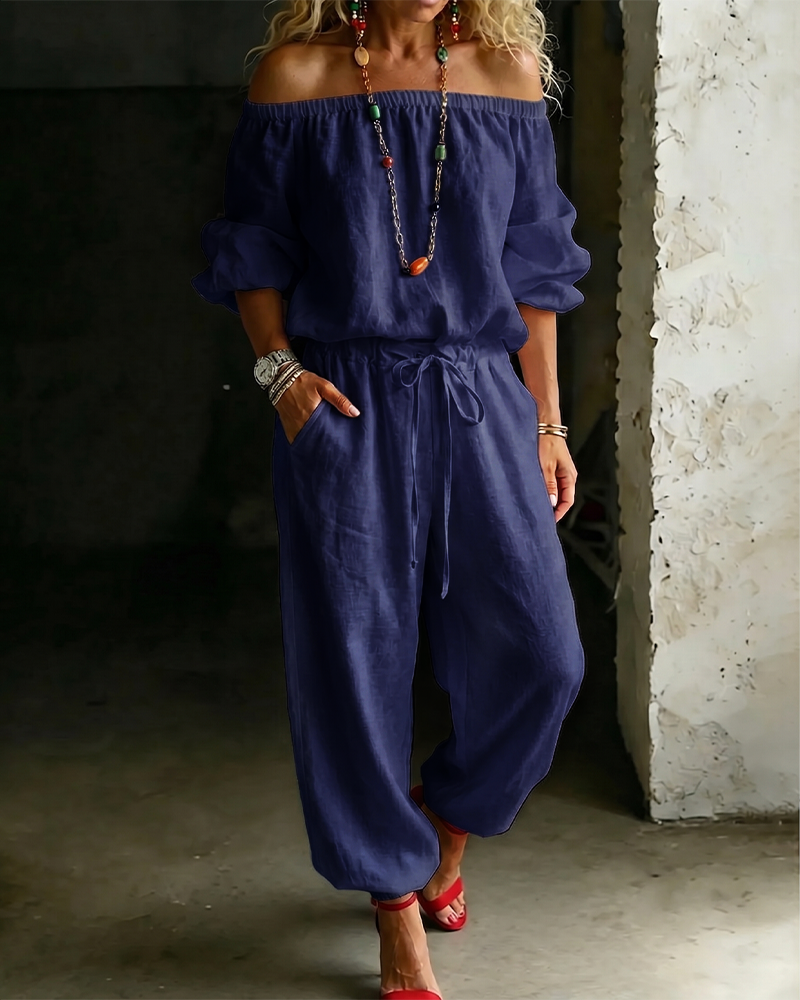 Model adjusting the tie-waist of the Rhiannon cotton jumpsuit, demonstrating its customisable fit.