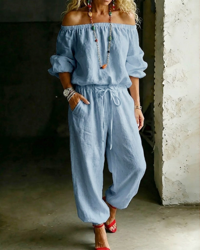 A lifestyle shot of the Rhiannon cotton jumpsuit worn with sandals and a sun hat, ideal for a sunny day out.