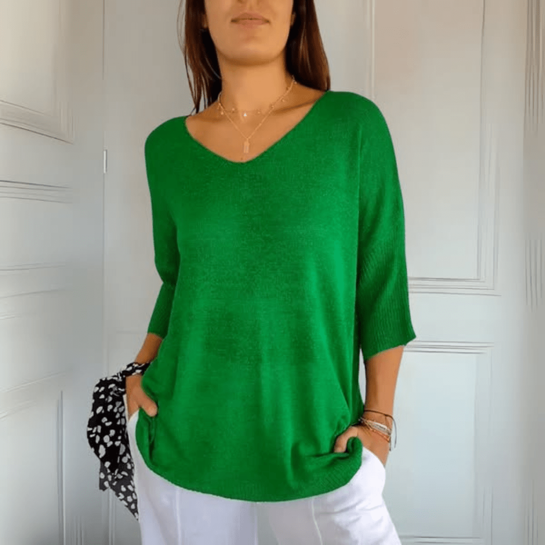 Lifestyle image of a woman enjoying a coffee, wearing the Ophelia V-Neck loose sweater in an outdoor setting.