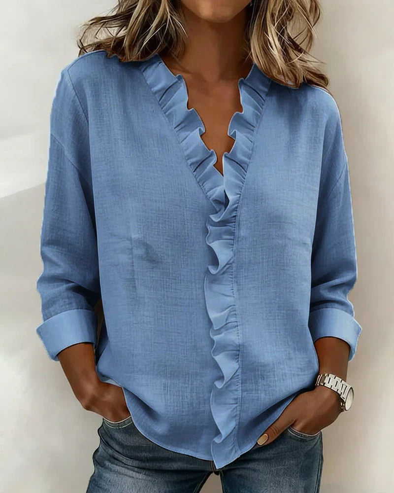 A model smiling while wearing the black Persephone long sleeve blouse, demonstrating its relaxed fit.