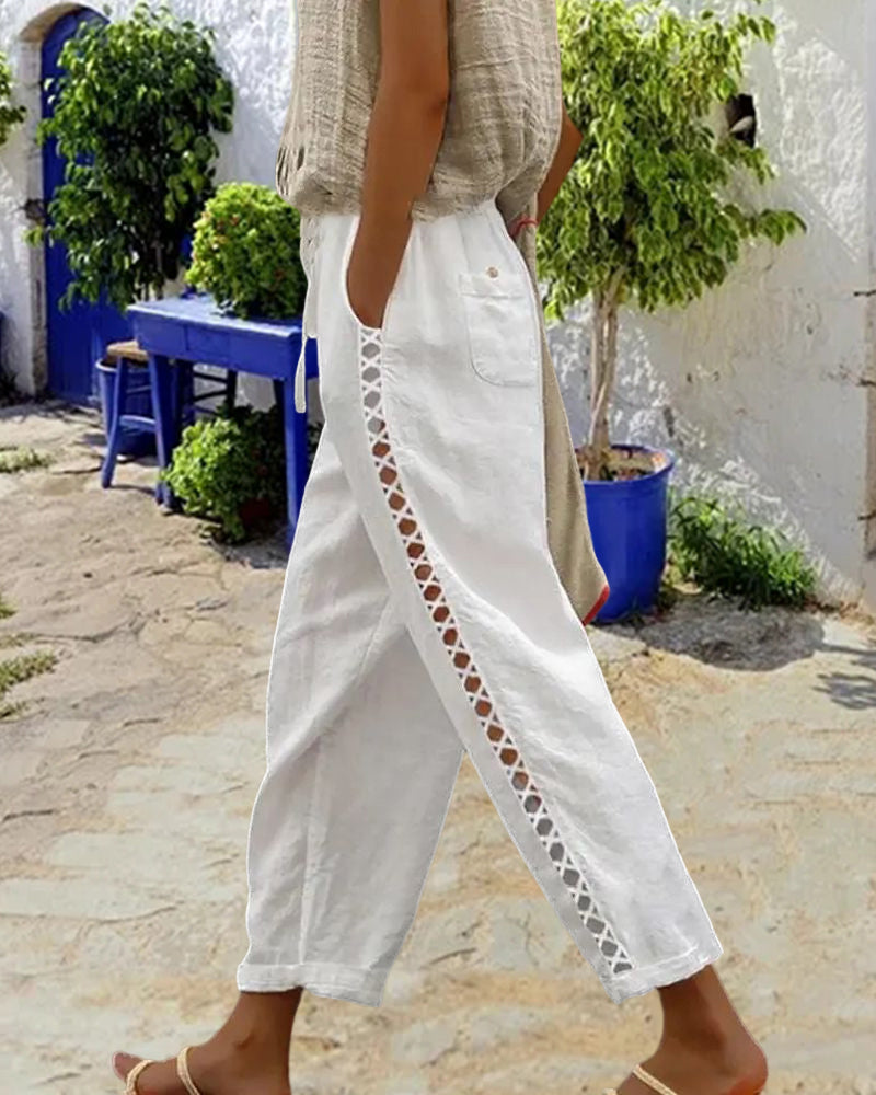 Side profile of a model wearing the white hollow-out linen trousers, highlighting the straight leg cut and mid-waist.