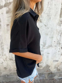 Detail of the stitching along the hem of a black Seraphina classic collared shirt, indicating craftsmanship.