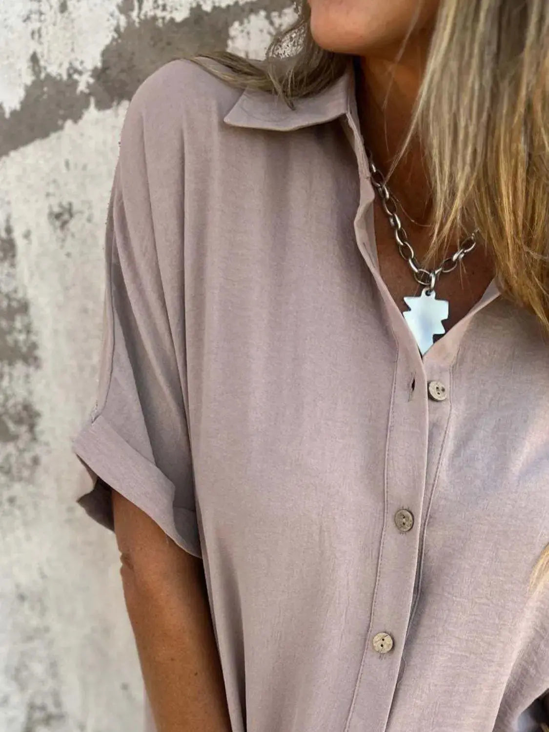 Lifestyle image of a woman pairing a dusty pink Seraphina classic collared shirt with smart trousers.