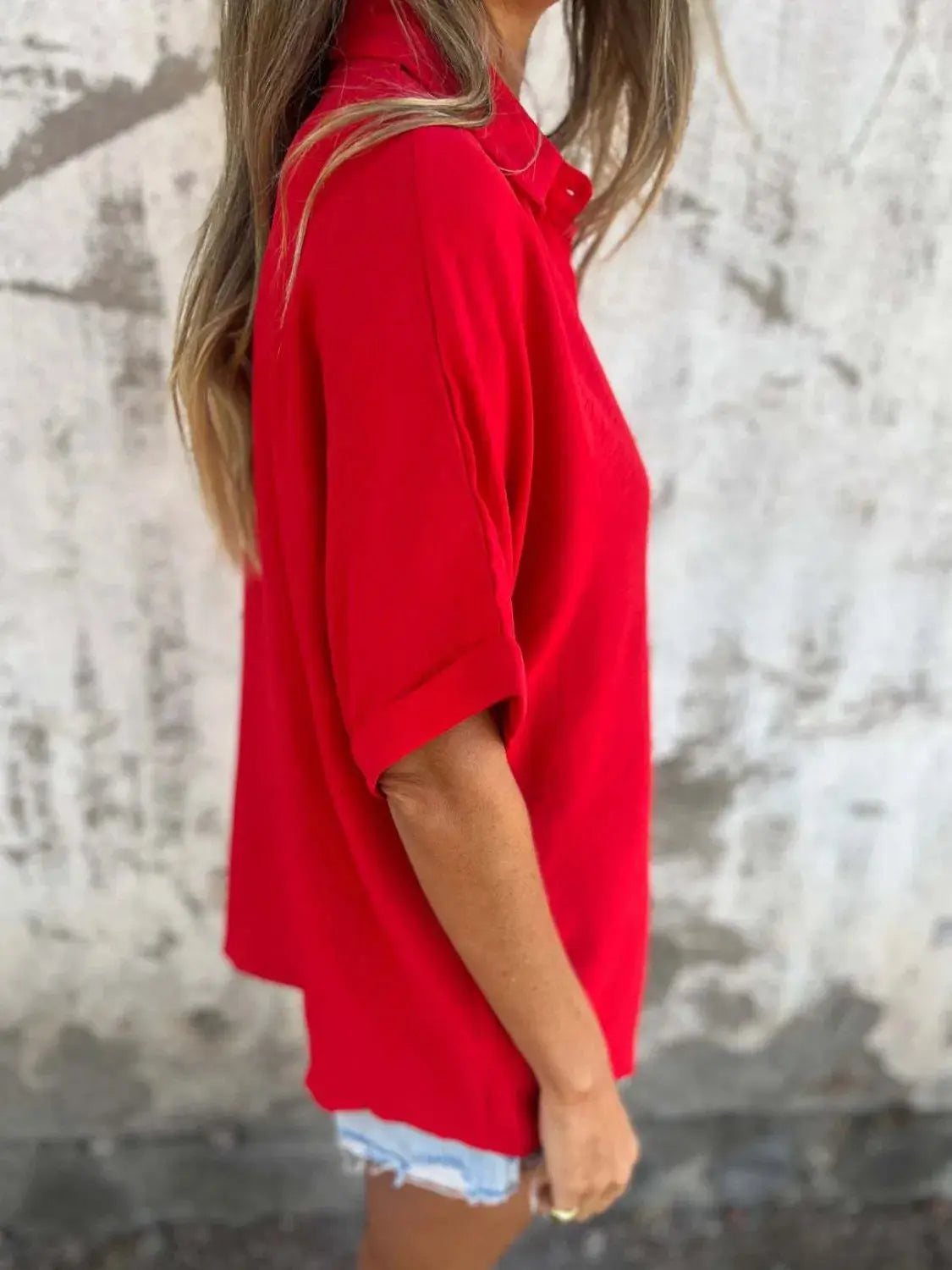 Woman adjusting the collar of her scarlet Seraphina classic collared shirt, focusing on the neckline.